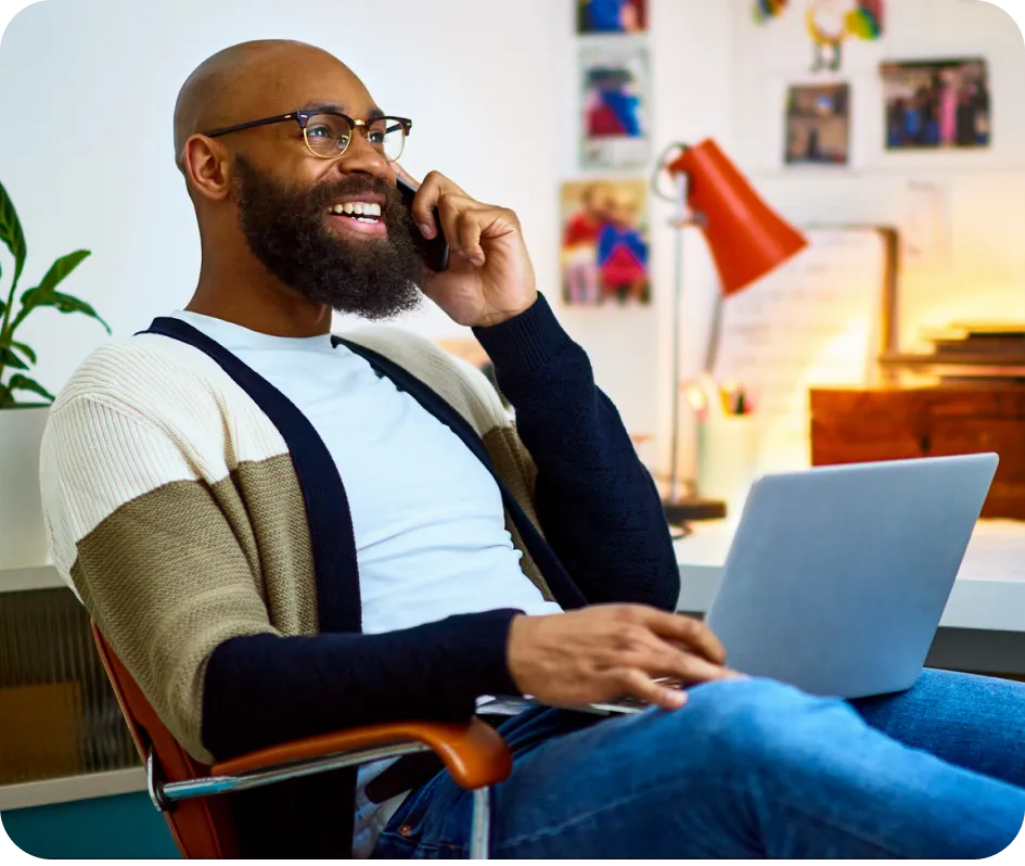 Dark-skinned person smiling and using their phone